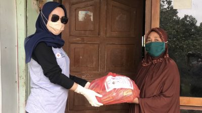 Ketua PMI Konawe, Titin Nurbaya Saranani secara simbolis menyerahkan bantuan paket sembako dan vitamin ke salah satu warga di Desa Amonggedo Kecamatan Amonggedo Kabupaten Konawe. (Foto/Aw)