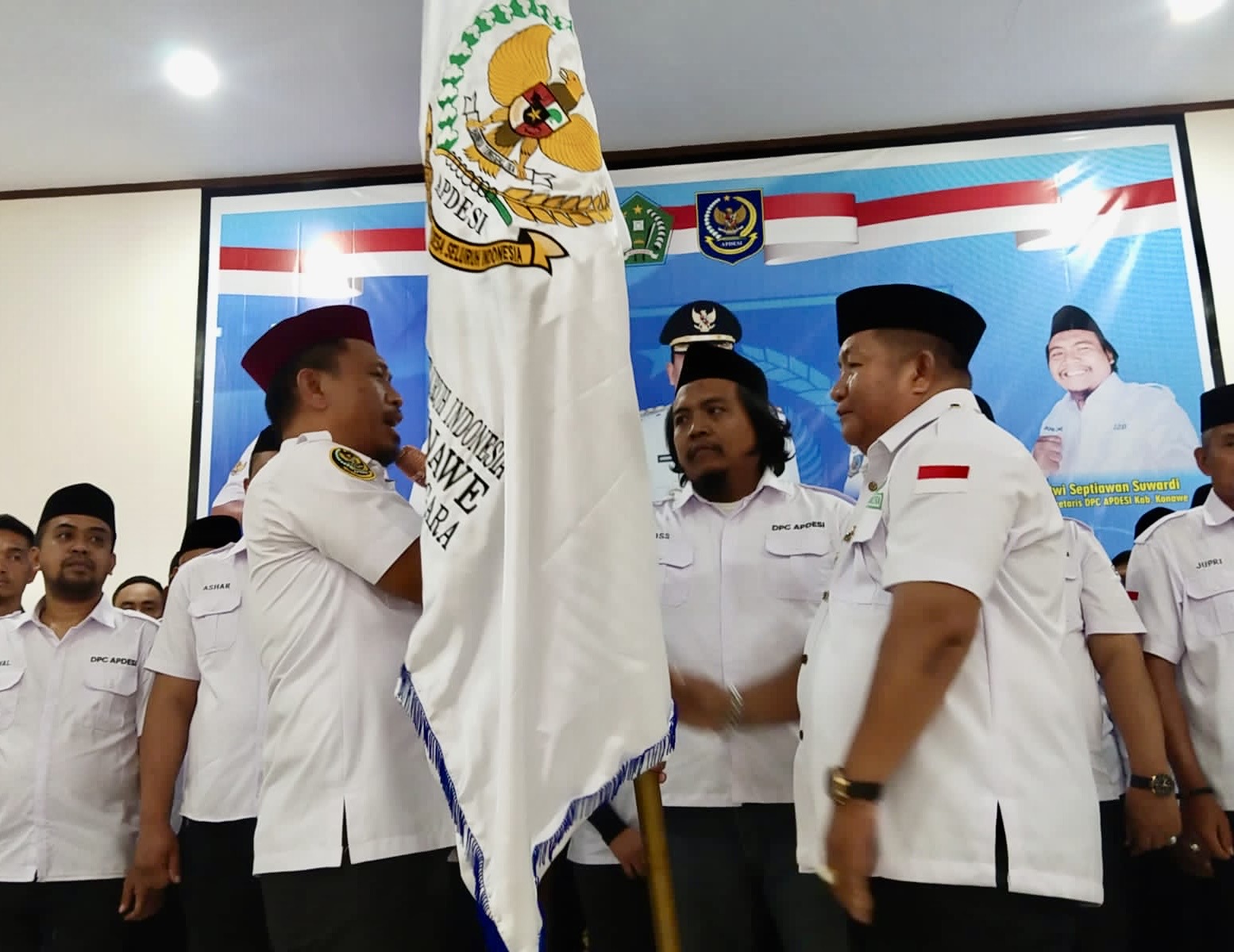 Ketua DPD APDESI Sulawesi Tenggara (Sultra), H. Tasman (kanan) saat menyerahkan Bendera Pataka kepada Ketua DPC APDESI Konawe, Jumar Lakarana, S.Pd, Selasa 10 Oktober 2023